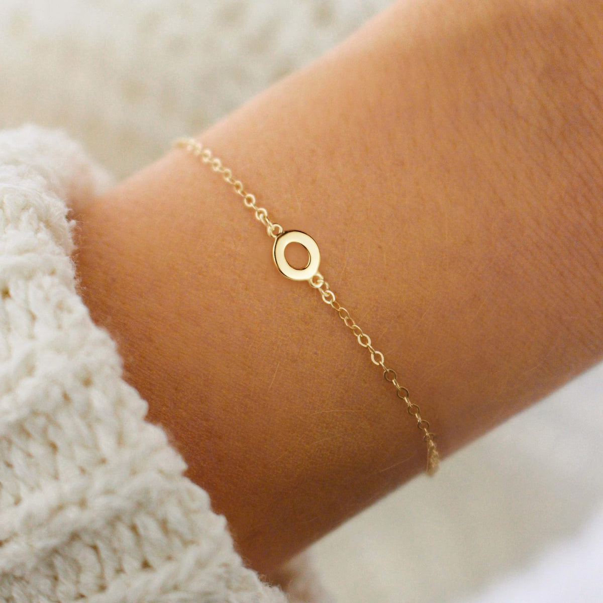 Gold initial O bracelet at the wrist - Pulse and Glow