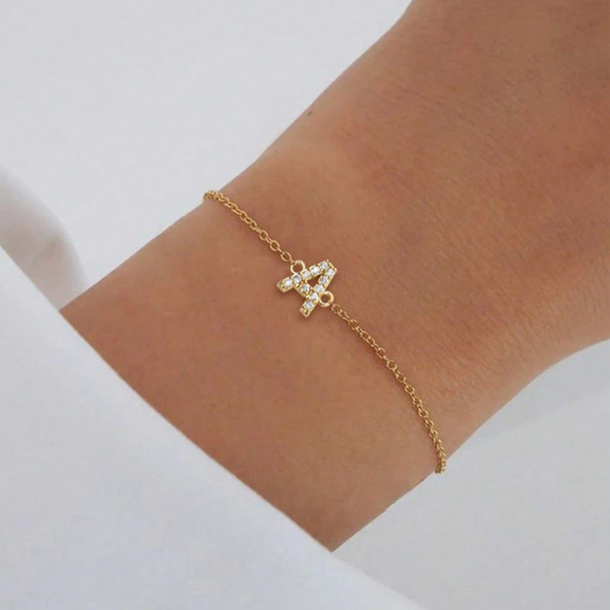Close detail of the crystal-set initial charm on the fine chain